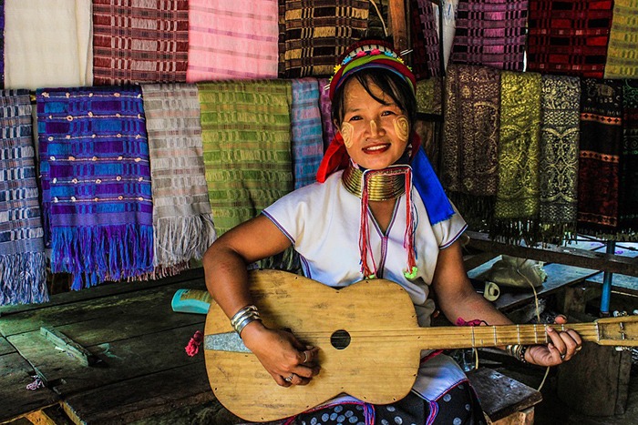 a Thai woman smiling while holding a guitar in a fabric shop