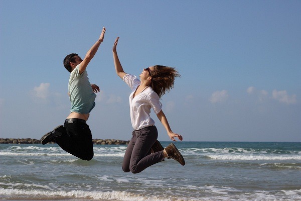 Two people jumping and high-fiving in the air