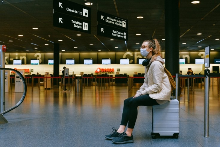 woman in an airport sitting on her luggage