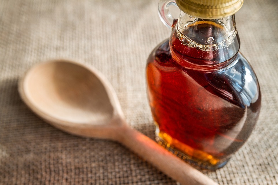 syrup inside a bottle, wooden spoon, brown carpet