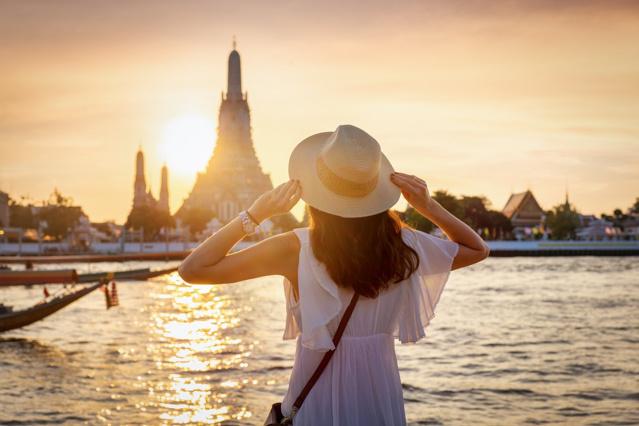 A tourist woman enjoys the view to the famous Wat Arun temple in Bangkok